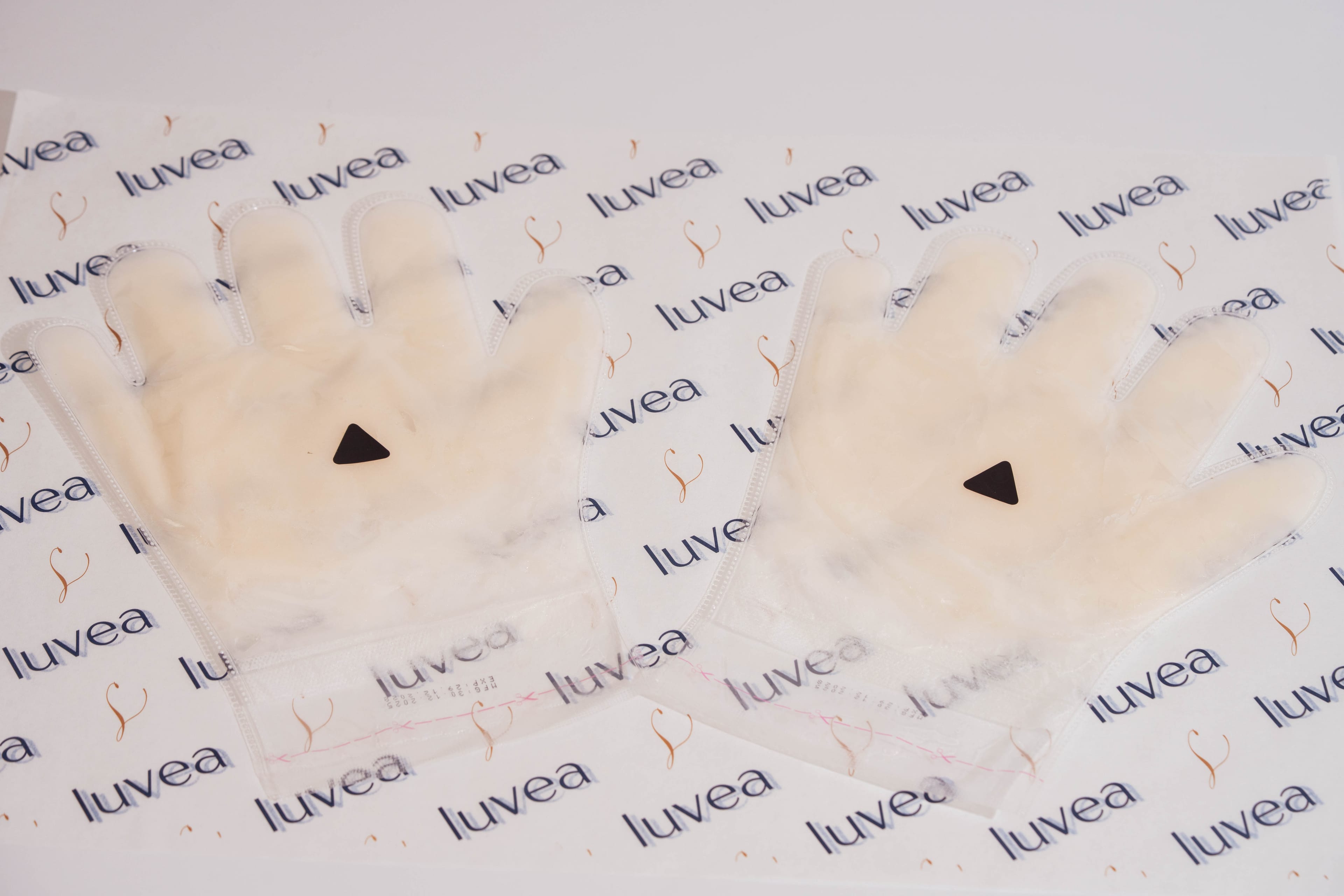 Pair of glove-shaped paraffin wax masks arranged on luvéa branded paper