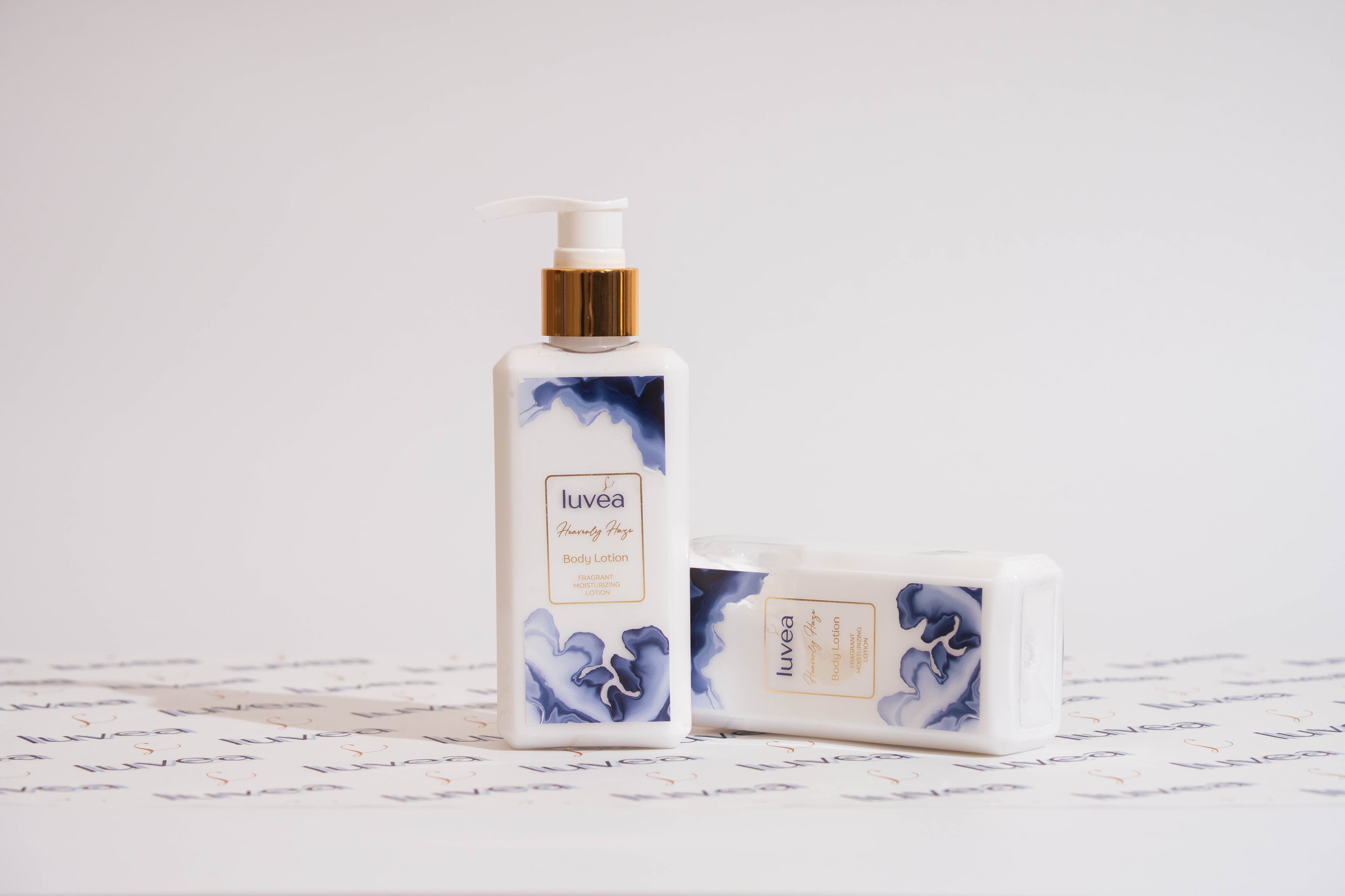 Two Heavenly Haze lotion bottles photographed straight on against luvéa-patterned paper