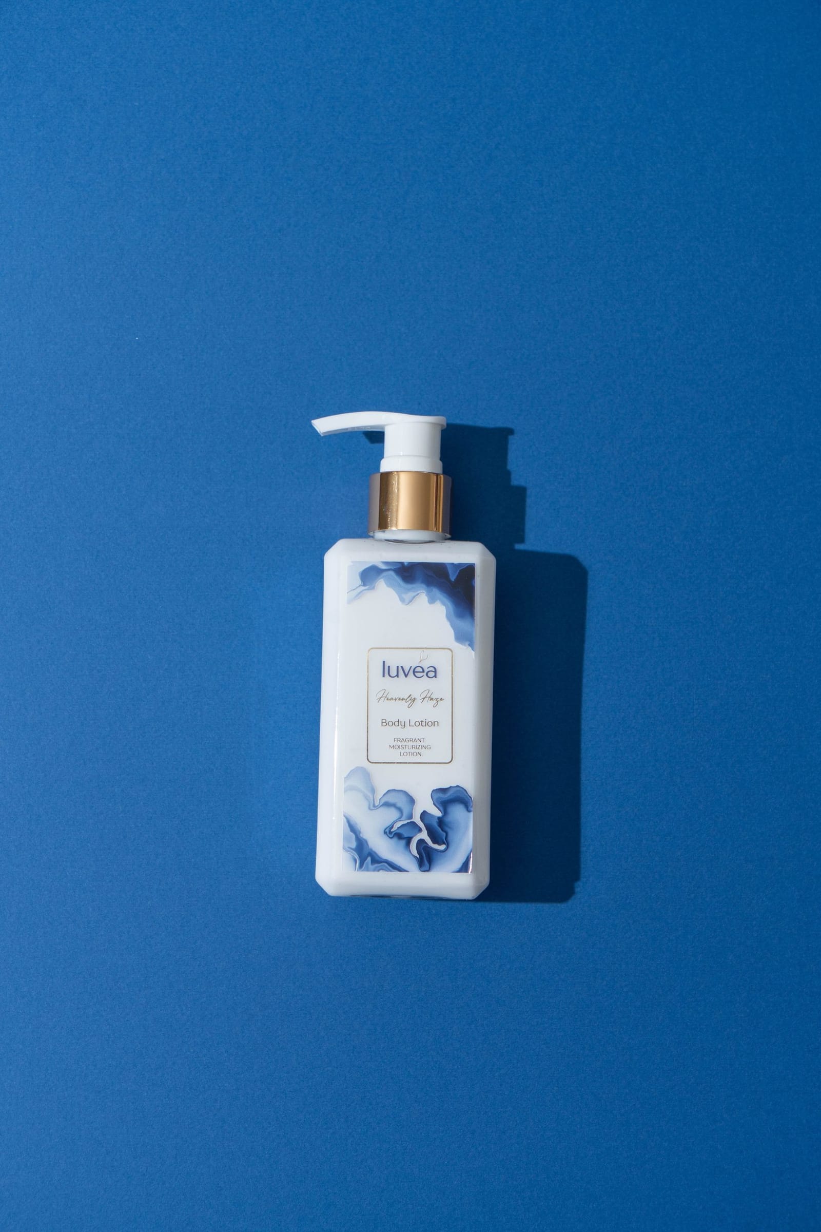 The luvéa Heavenly Haze body lotion bottle, white with a gold collar and marbled blue label